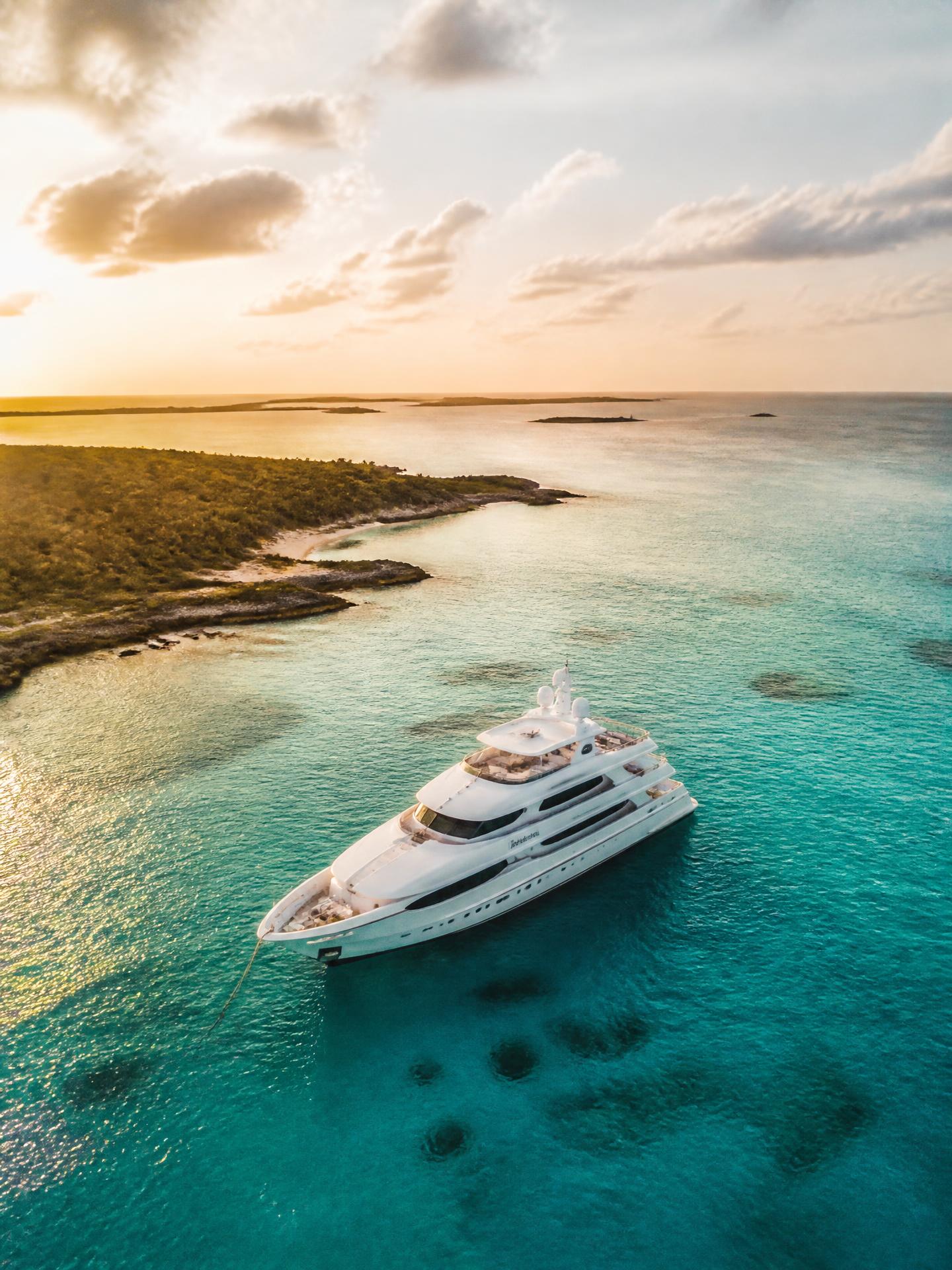 Aerial view of a luxury yacht on turquoise Bahamian water at sunset